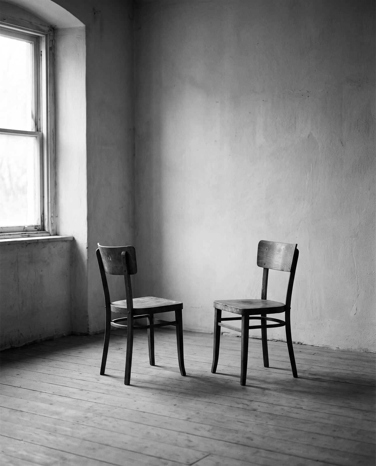 Two empty chairs facing each other in a bare room
